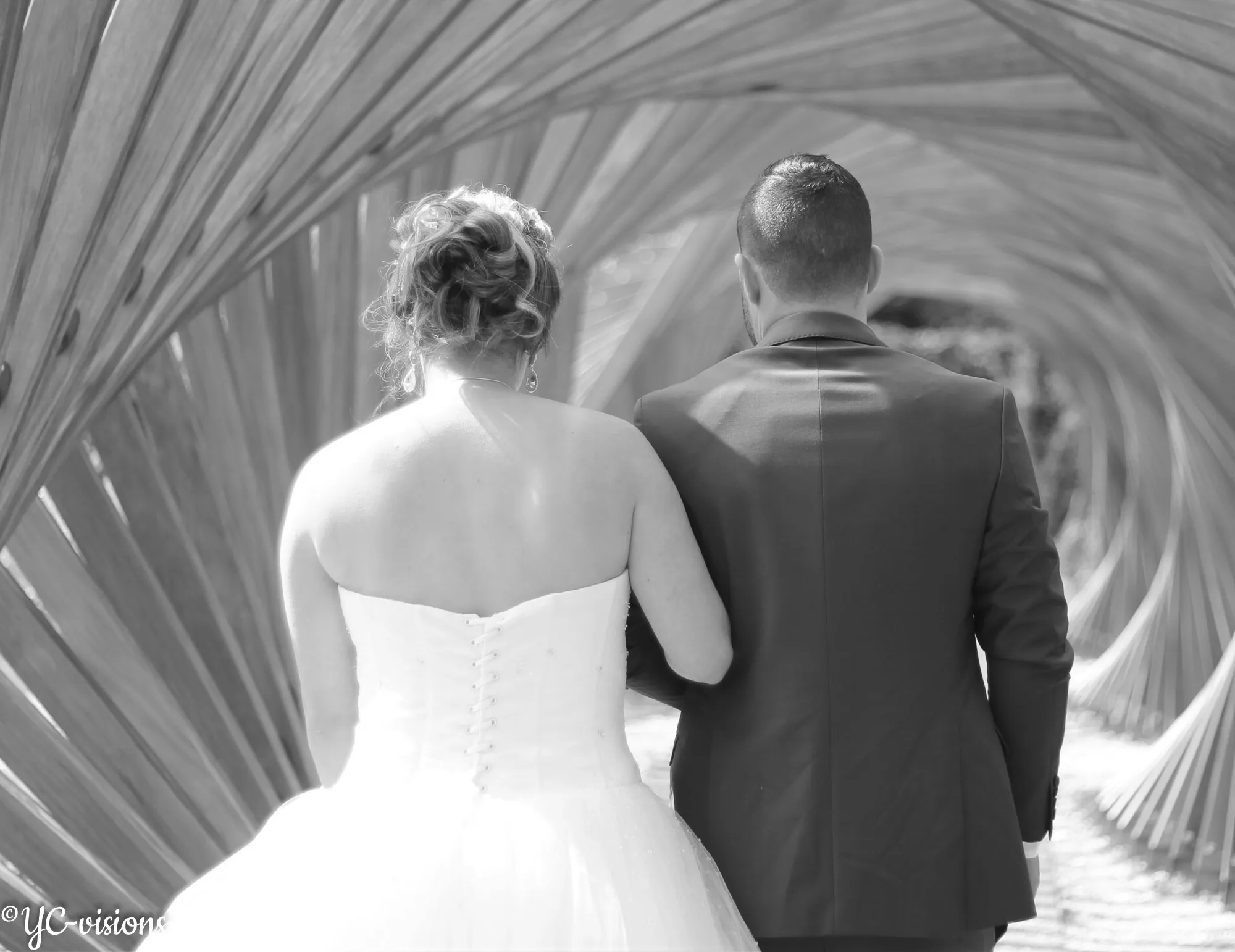 Couple de mariés photographié en noir et blanc sous une arche